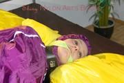 Lucy tied and gagged on a bar in bed wearing a sexy purple rainwear combination (Pics)