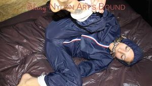 Sexy Sandra wearing a sexy shiny nylon rainwear combination being tied hand to feet and gagged with a cloth gag on a sofa (Pics)