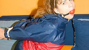 Leonie tied and gagged on a sofa wearing shiny nylon rainwear (Pics)