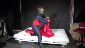 Watching Sonja wearing supersexy red/blue shiny nylon rainwear preparing her bed with shiny nylon cloth (Video)