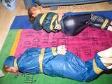 Stella and Leonie tied and gagged and hooded with tape both wearing sexy shiny nylon rainwear (Pics)