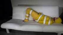 Watching Pia wearing a sexy yellow rainwear being tied and gagged with tape and a ballgag on a sofa (Video)