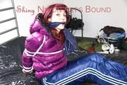 Mara tied and gagged on bed wearing a shiny purple down jacket and a blue rain pants (Pics)