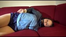 Lucy tied and gagged on a red sofa wearing a supersexy blue shiny nylon shorts and a blue rain jacket (Video)