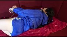 Lucy ties and gagges herself on a sofa with cuffs wearing a sexy blue shiny nylon shorts and a rain jacket (Video)