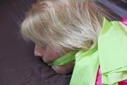 Pia in a green shiny nylon shorts with white stripes and a pink rain jacket tied and gagged in a bed (Pics)