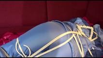 Lucy tied and gagged with a long rope on a sofa wearing a sexy oldschool skibib in blue (Video)