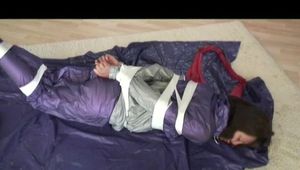 A video with Alina tied and gagged in a shiny purple and silver PVC suit