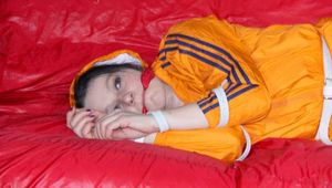 Lucy tied and gagged on a sofa wearing an orange shiny nylon rain jacket and a blue rain pants (Pics)