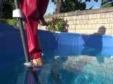 Watch Sandra watering the garden and wetting her shiny nylon oldschool Rainsuit in the Pool