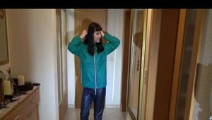 Mara wearing a blue rain pants and a green rain jacket preparing and appraising herself before going out (Video)
