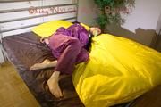 Lucy tied and gagged on a bar in bed wearing a sexy purple rainwear combination (Pics)