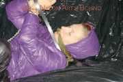 Sandra tied and gagged on a sofa with cuffs and a pillory wearing hot purple down jacket and black down pants (Pics)