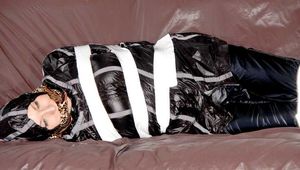 Mara wearing a sexy shiny black rian pants and a sexy shiny black rain jacket tied and gagged with tape and cloth gag on a sofa (Pics)
