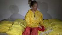 Watching Sandra  wearing an orange shiny nylon rain pants and a yellow shiny nylon rain jacket being tied and gagged on a bed with ropes and a clothgag (Video)