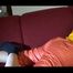 Lucy wearing an orange rain pants and a yellow rain jacket lolling on the sofa and reading a bit (Video)