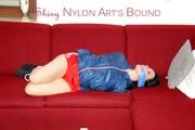 Lucy tied and gagged on a red sofa wearing a supersexy red sprinter and a blue rain jacket (Pics)