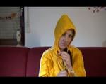 Lucy wearing an orange rain pants and a yellow rain jacket lolling on the sofa and reading a bit (Video)