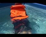 Mara wearing a sexy darkblue rain pants and rain jacket testing a life jacket in the swimmingpool (Video)