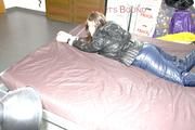 Shelly tied and gagged on a bed with downjacket and shiny rainsuit