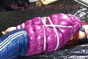 Mara tied and gagged on bed wearing a shiny purple down jacket and a blue rain pants (Pics)