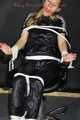 Sexy Sandra being tied and gagged on a haircutter`s chair with ropes and a ball gag wearing a supershiny sexy black rain bib overall (Pics)