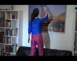 Mara wearing a shiny nylon rain pants and a rain jacket while cleaning up the living room (Video)