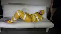 Watching Pia wearing a sexy yellow rainwear being tied and gagged with tape and a ballgag on a sofa (Video)