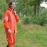 Miss Petra macht einen Spaziergang in einem orangen AGU Regenanzug und Gummistiefel