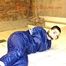 Jill tied and gagged in an old cellar on the floor wearing a shiny blue PVC sauna suit (Pics)