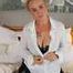 Busty blonde Frida posing in white shirt, leather corsage and black glossy leggins on bed