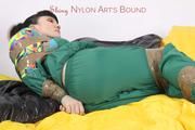 Jill tied and gagged with tape on bed wearing a shiny green nylon rainsuit (Pics)