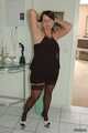 Chubby Benita posing in a black dress, stockings and heels