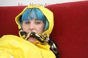 Mara tied, gagged and hooded with tape on a red sofa wearing shiny yellow rainwear (Pics)