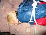 Beautiful archive girl bare feet tied and gagged in a dark blue short with light blue stripes and a red/blue rain jacket on a sofa