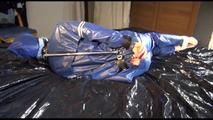 Pia tied, gagged and hooded in bed wearing a sexy blue AGU rainwear combination (Video9