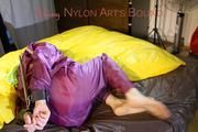 Lucy tied and gagged on a bar in bed wearing a sexy purple rainwear combination (Pics)