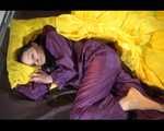 Lucy wearing a purple rain suit preparing her bed cloths for enjoying herself and the rain suit in bed lolling around (Video)