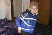 Pia tied, gagged and hooded on a bed wearing a sexy black shiny nylon pants and a blue/black down jacket (Pics)