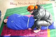 An archive girl tied and gagged in a sleepingsack by Jill on the floor both wearing shiny down jackets (Pics)