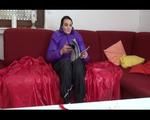 Jill wearing a blac rain pants and a purple down jacket feeling herself on a red sofa (Video)