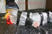Pia tied and gagged with tape on a bed wearing a sexy silver rainwear combination (Pics) 