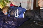 Pia tied, gagged and hooded on a bed wearing a sexy black shiny nylon pants and a blue/black down jacket (Pics)