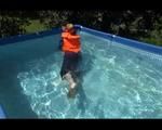 Mara wearing a sexy darkblue rain pants and rain jacket testing a life jacket in the swimmingpool (Video)