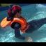 Mara wearing a sexy darkblue rain pants and rain jacket testing a life jacket in the swimmingpool (Video)