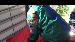 Lucy wearing green rainwear while putting on clean shiny nylon linen (Video)