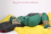 Jill tied and gagged with tape on bed wearing a shiny green nylon rainsuit (Pics)