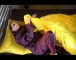 Lucy wearing a purple rain suit preparing her bed cloths for enjoying herself and the rain suit in bed lolling around (Video)